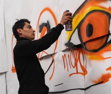 Fotografía de artista con aerosol en la mano pintando