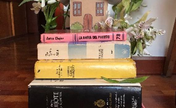 Fotografía de escultura Triatlón Domestico libros apilados con una casa pequeña y plantas